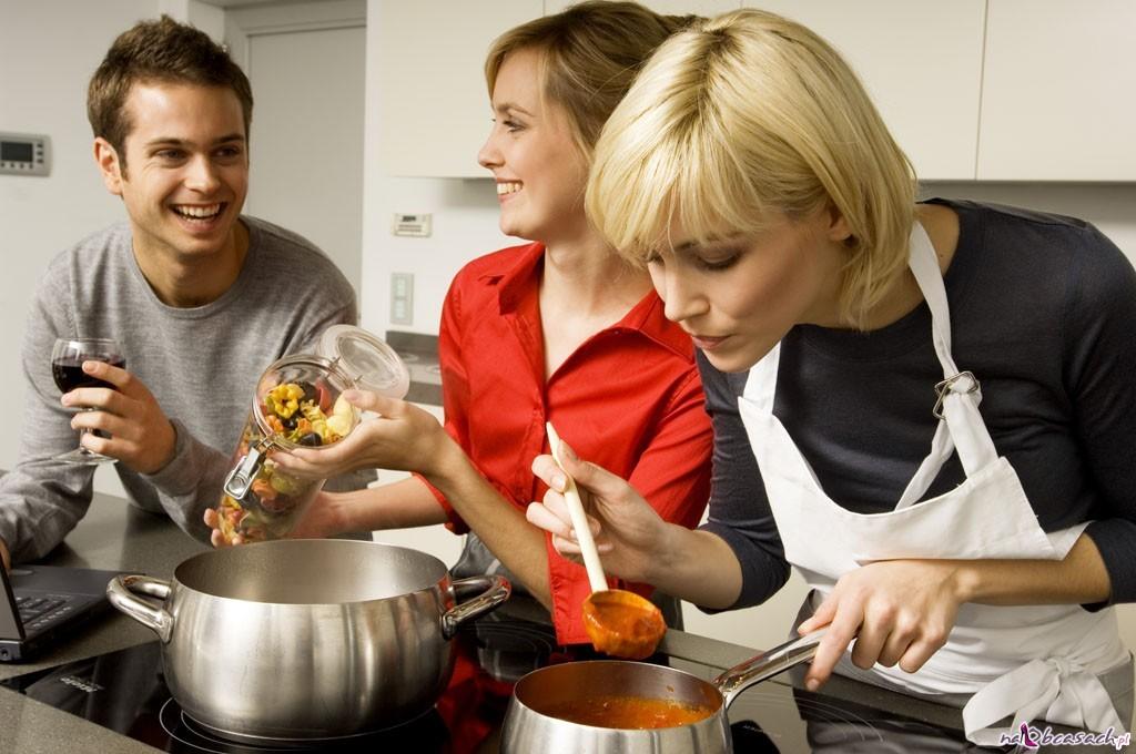 Two young women and a young man preparing food in the kitchen