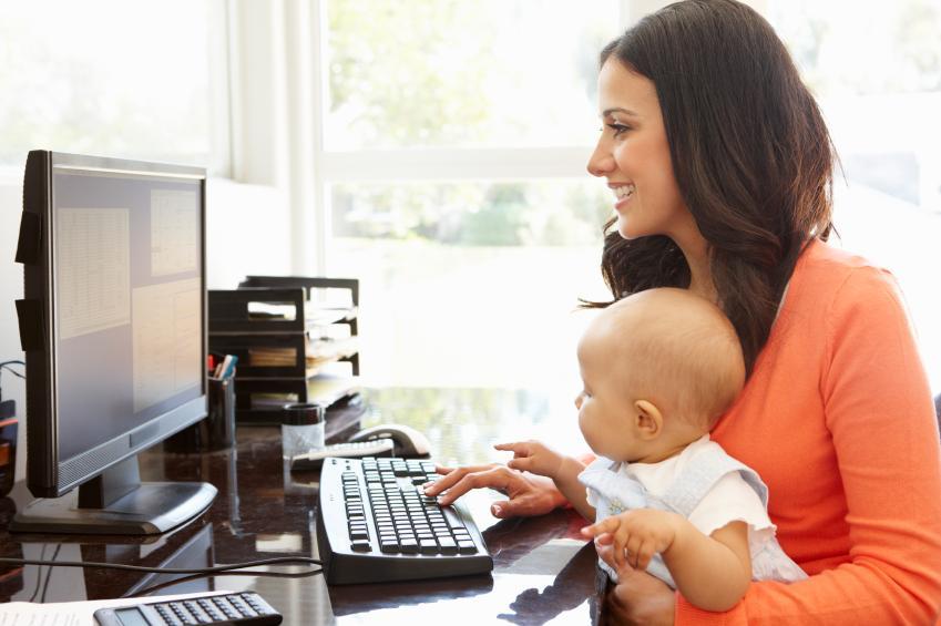 Hispanic mother with baby working in home office