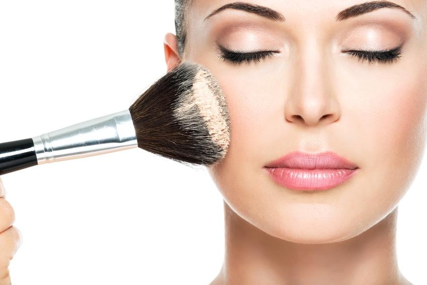 woman  applying dry cosmetic tonal foundation  on the face