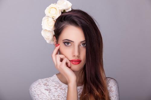 Beautiful woman flowers in head on grey background