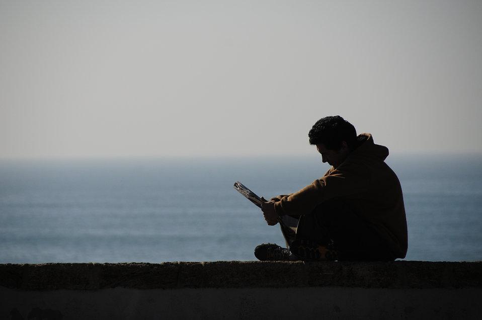 9748-silhouette-of-a-man-reading-by-the-ocean-pv