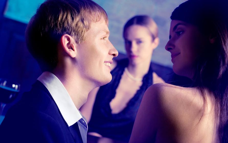 Young couple and woman looking at them at club