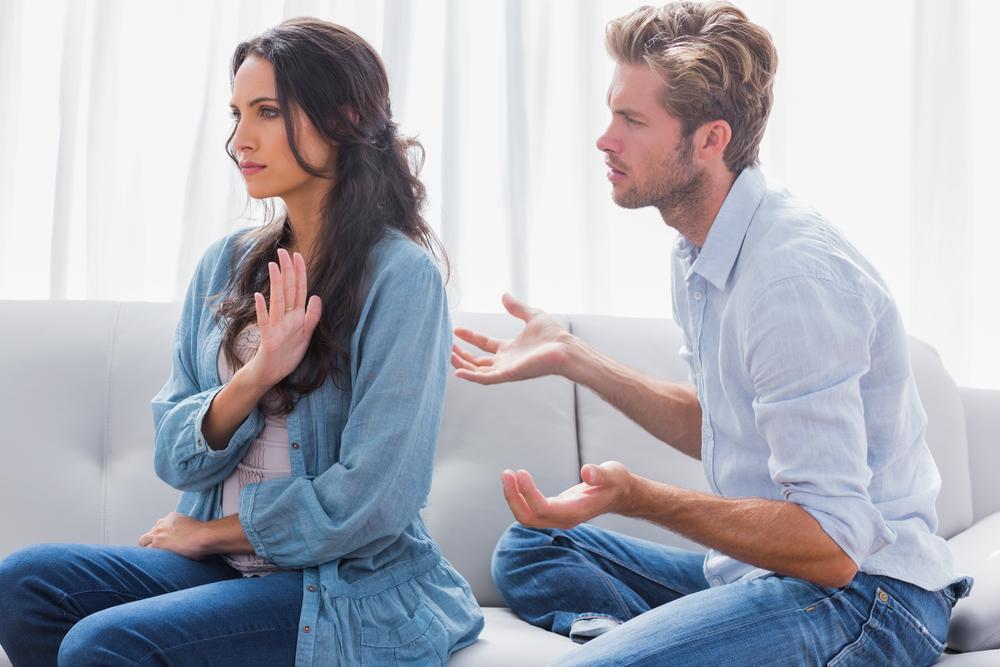 Woman gesturing while quarreling with her partner in the living room