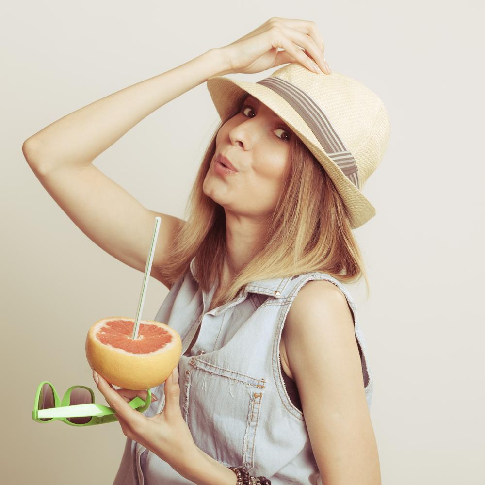 Woman in hat drinking grapefruit juice. Diet