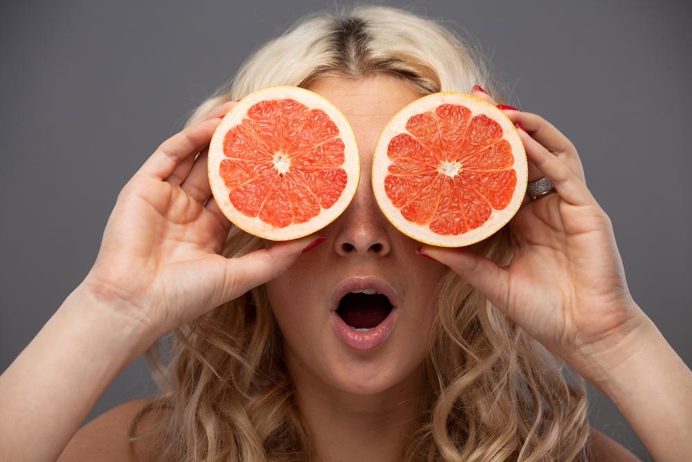 Smiling woman holding two grapefruits in hands