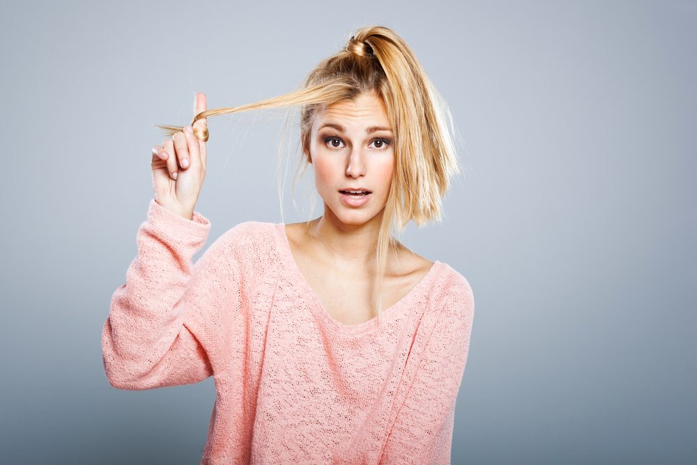 Young Blond Girl with Hair Problems ona Grey Background