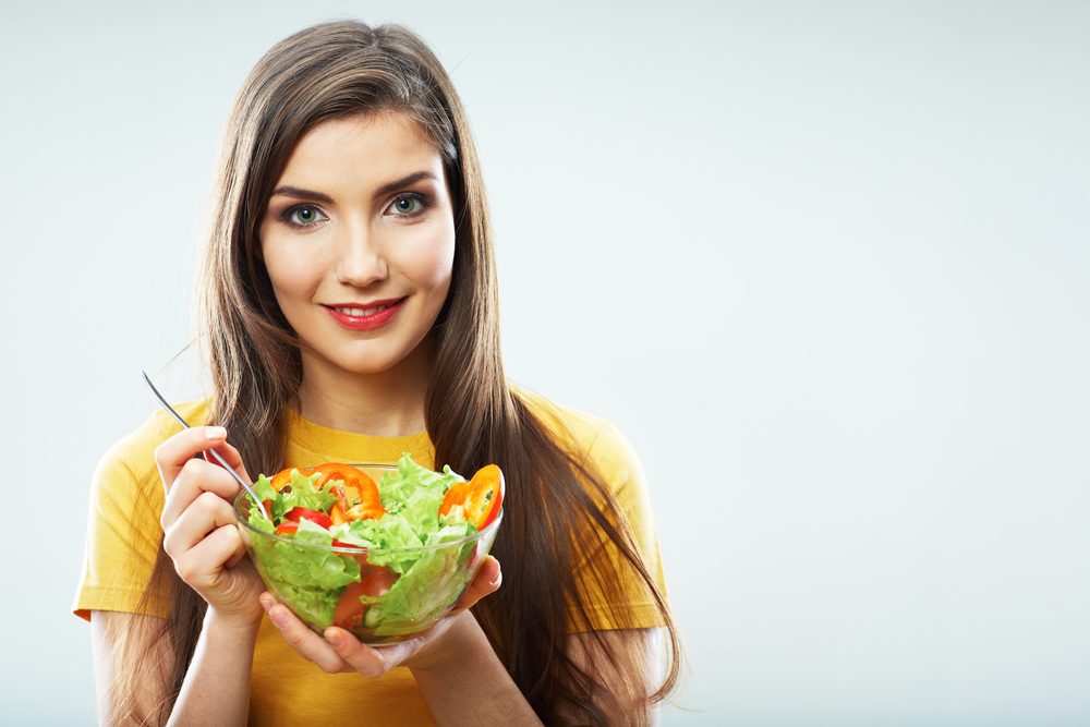 Woman diet concept portrait. Female model hold green salad. Isolated portrait.