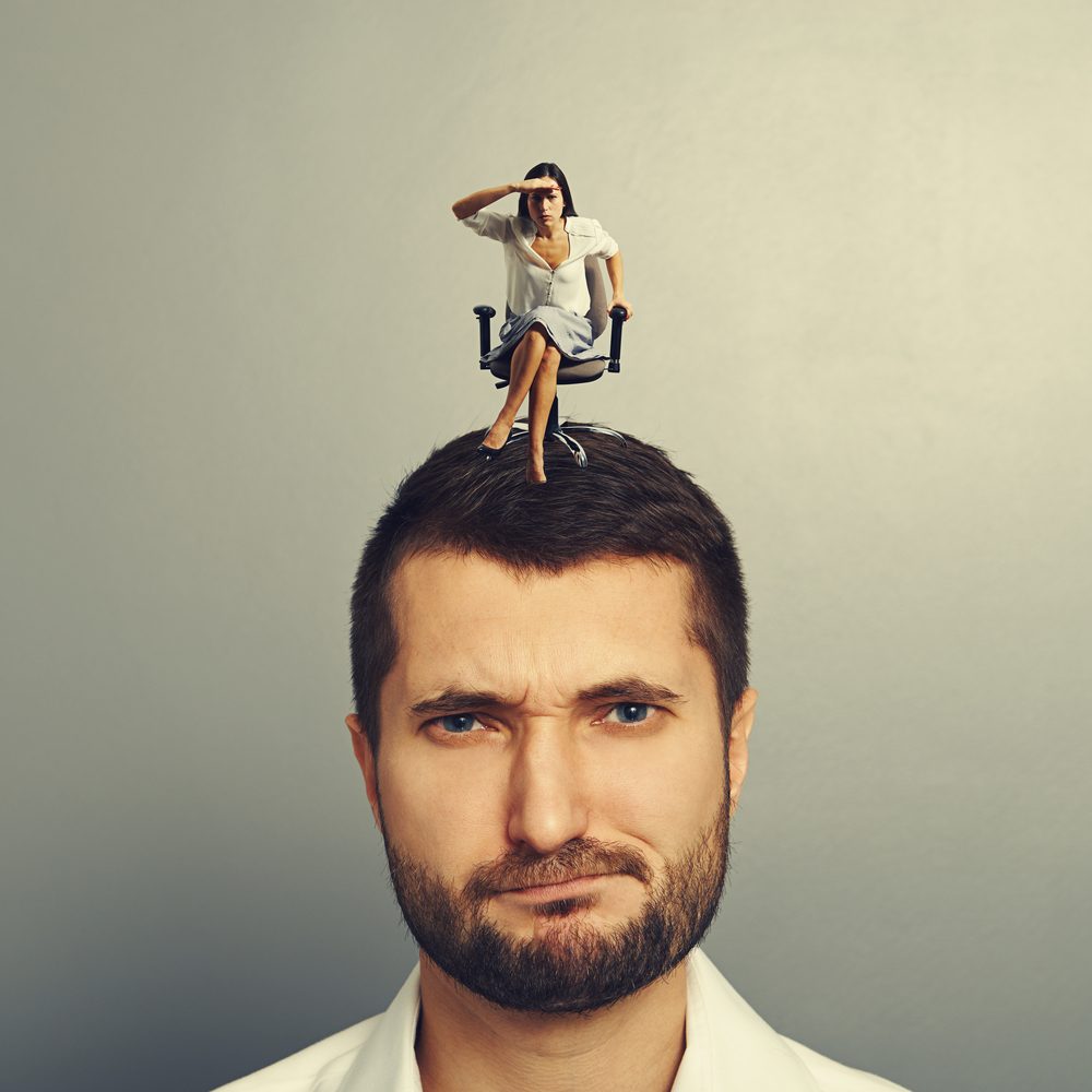 concentrated woman siting on the dissatisfied man and looking into the distance