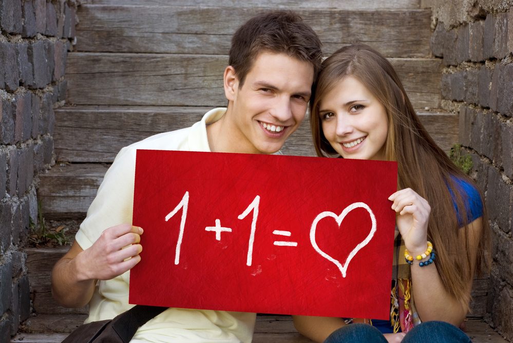 Young couple is holding board with romantic symbol.