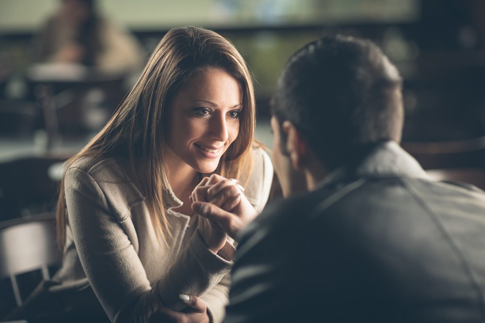 Romantic young couple dating and flirting at the bar, staring at each other's eyes