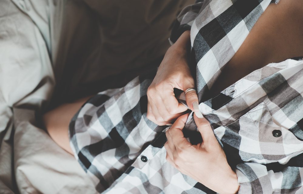 Soft photo of woman in checkered shirt on the bed, top view point