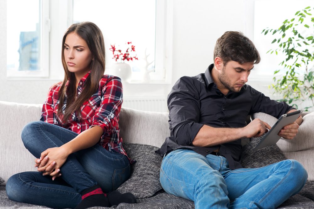 young couple in conflict, male with a tablet in hands