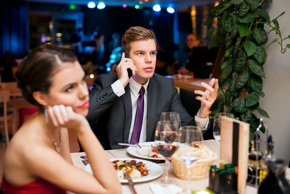 Man talking on a cell phone while on a date with his girlfriend or wife