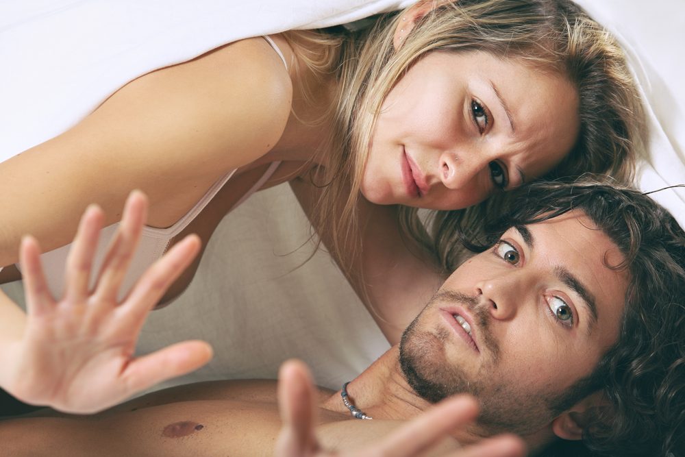 Man and woman with shocked expression under the sheet. Fear and adultery concept