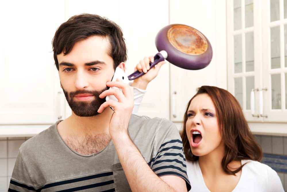 Young rage woman hitting her talking partner with frying pan.