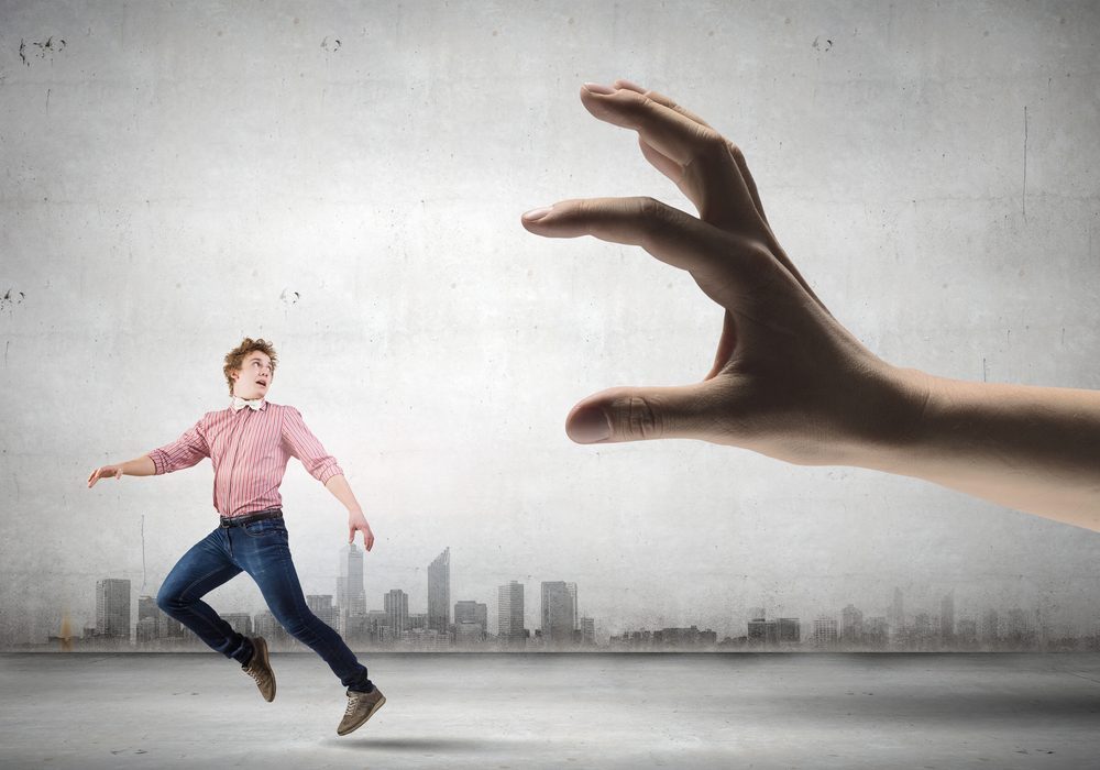 Young man trying to run away from big male hand