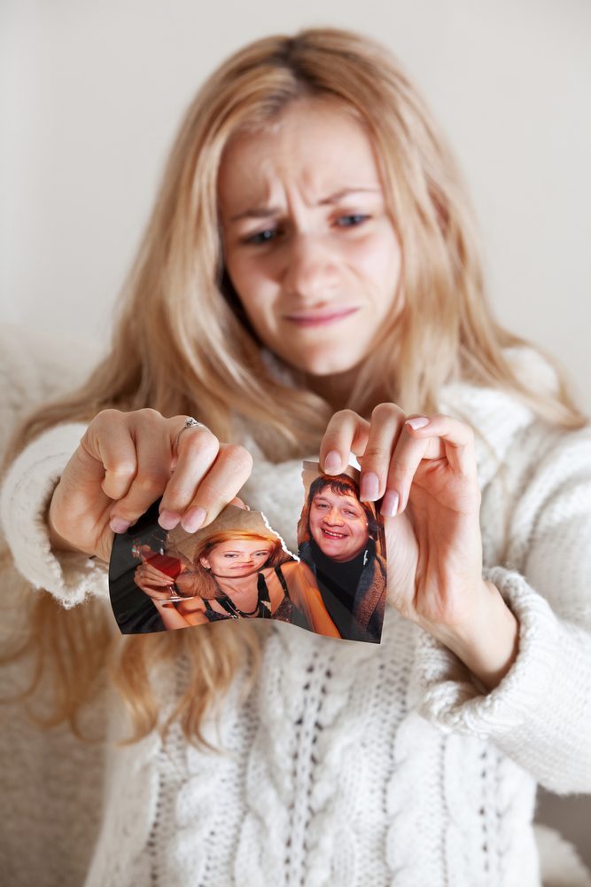 Sad woman, tearing a family photo