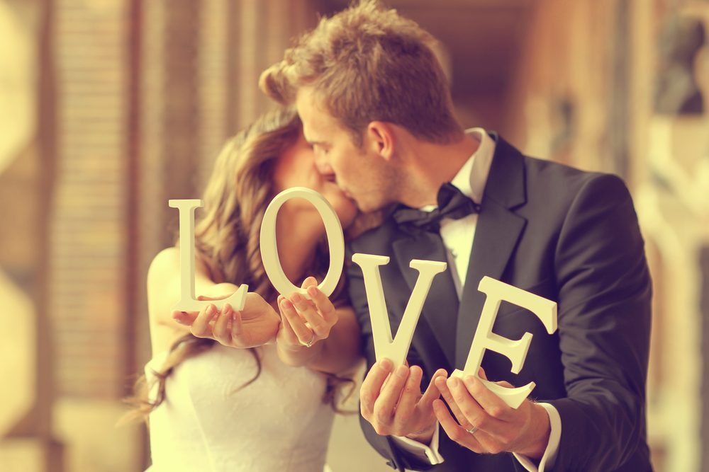 Happy bride and groom holding LOVE letters