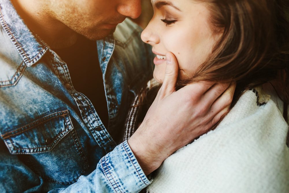 Young couple in love wrapped in plaid standing and looking at each other