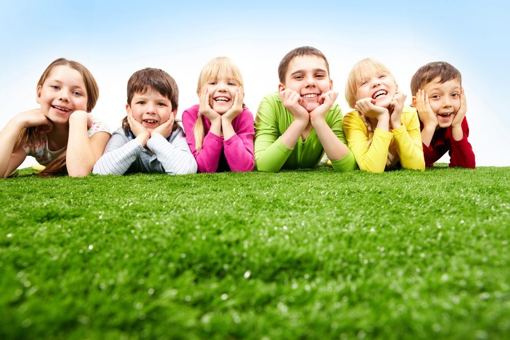 Image of happy boys and girls lying on a green grass