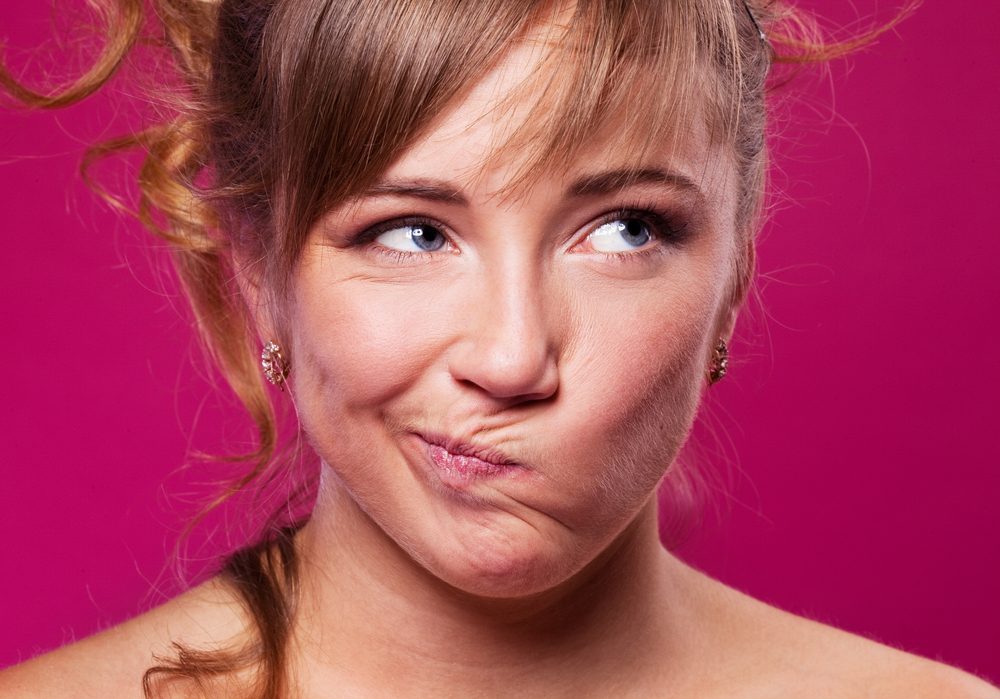 portrait of a displeased young woman, isolated against purple studio background