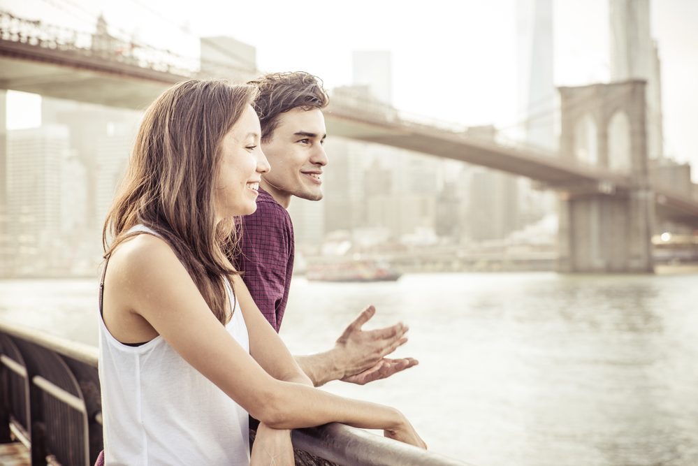 Happy couple talking in front the famous Brooklyn bridge. Concept about traveling, landmarks and people