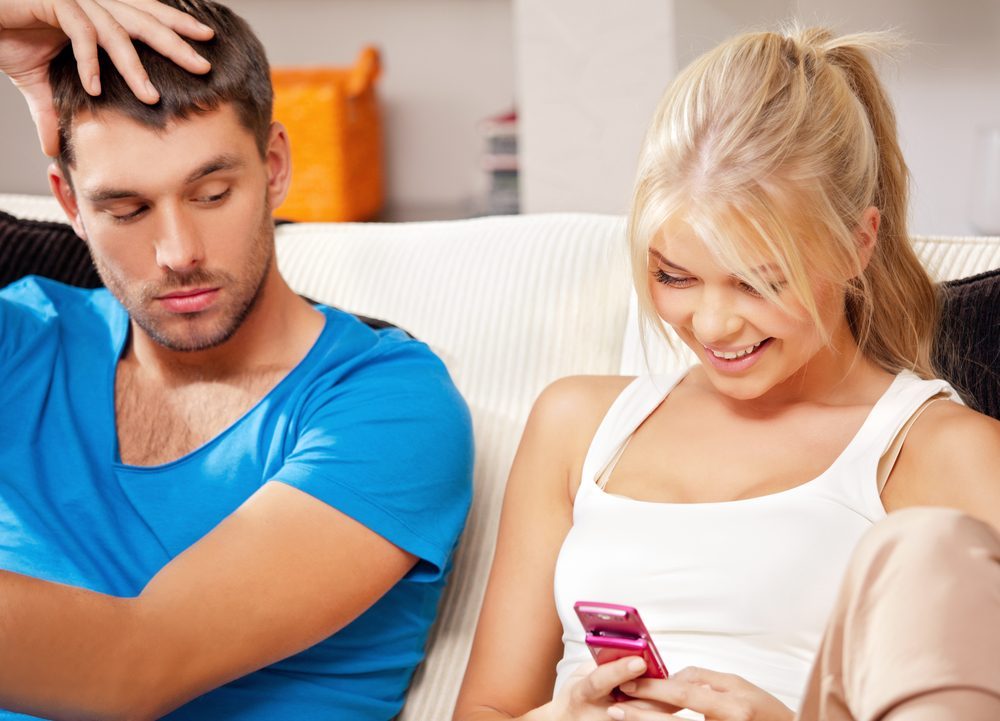 bright picture of couple at home with cellphone (focus on woman)