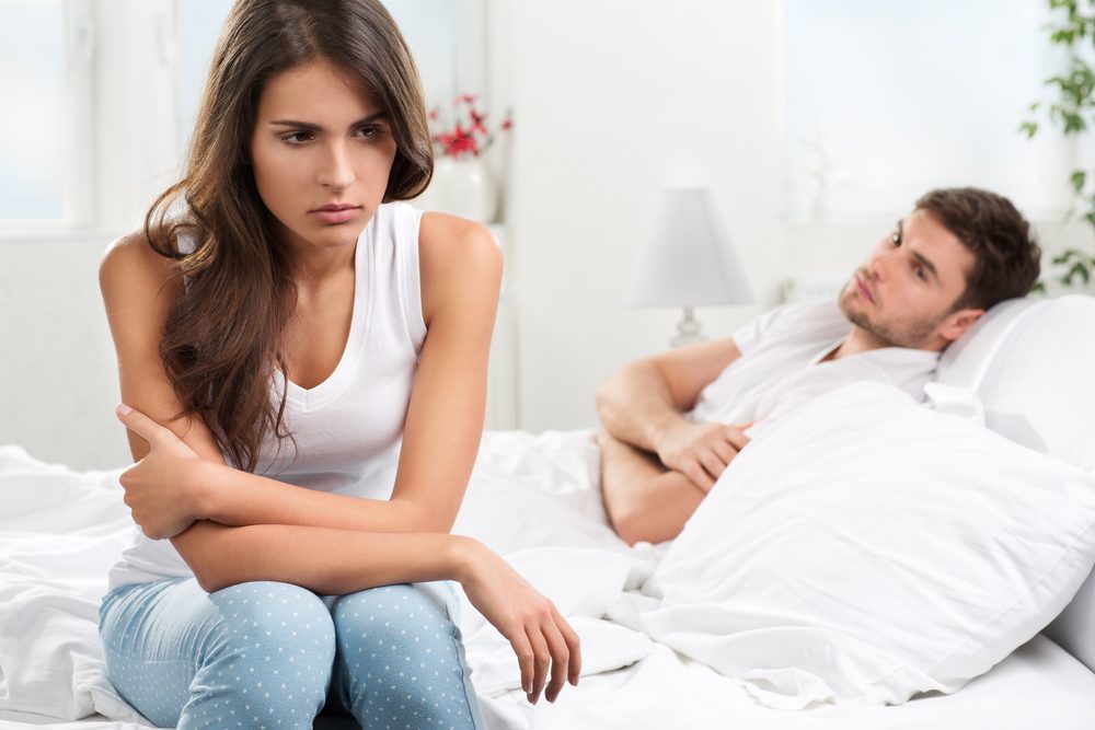 Portrait of unhappy young heterosexual couple in bedroom