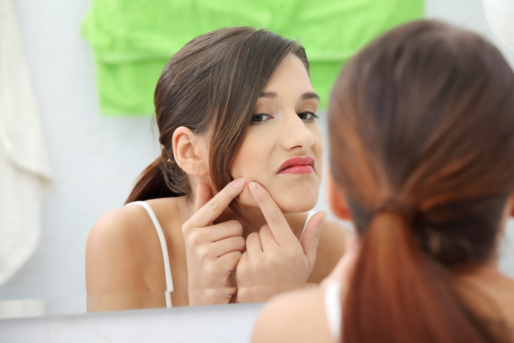 Young teenage woman with pimple on her face