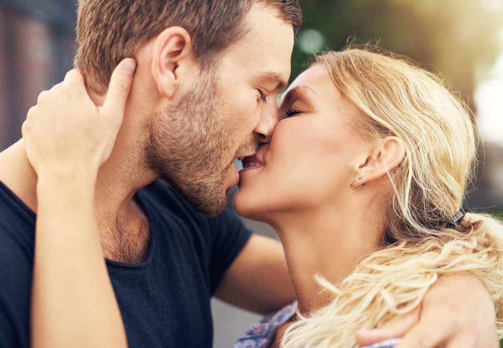 Young couple deeply in love sharing a romantic kiss, closeup profile view of their faces