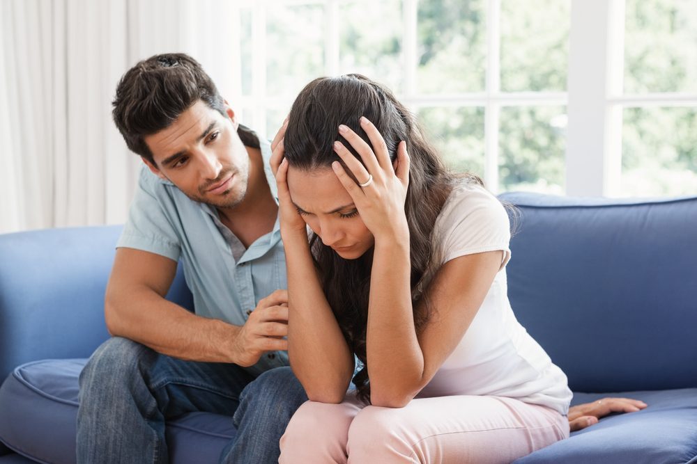 Man comforting his upset partner at home in living room