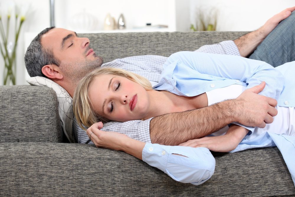 Husband and wife sleeping on their couch