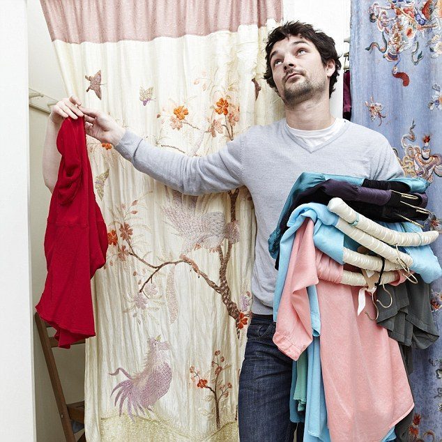 Man holding clothes by a changing room --- Image by © Liam Norris/cultura/Corbis