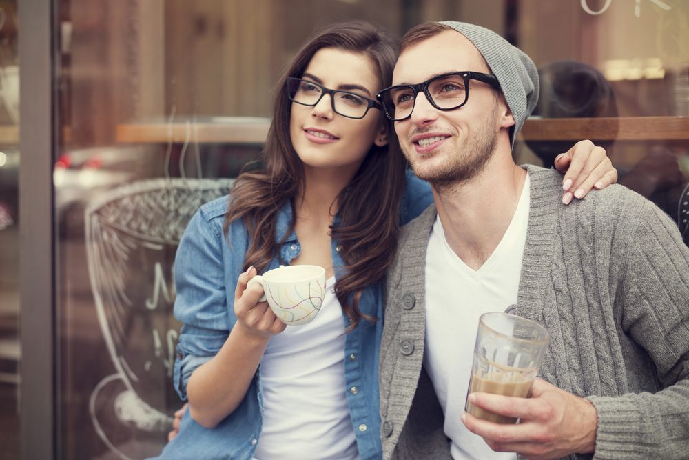 Young fashion couple drinking coffee outside of cafe