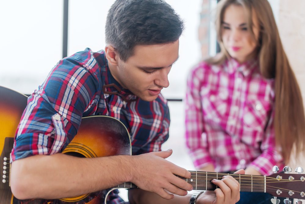 Young man singing playing guitar for his girlfriend.