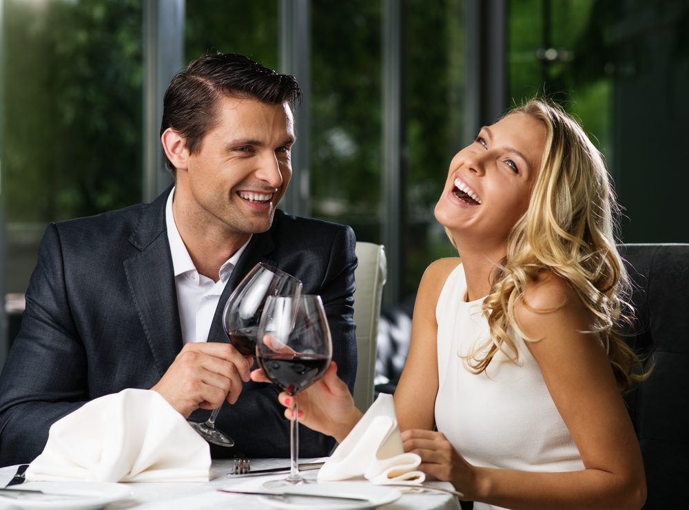 Cheerful couple in a restaurant with glasses of red wine