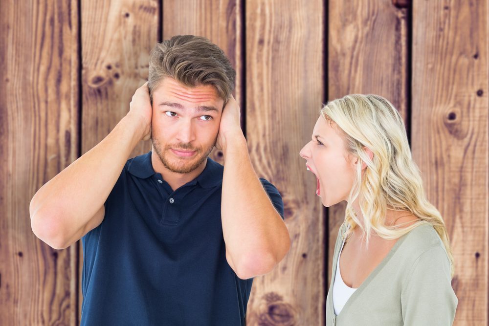 Man not listening to his shouting girlfriend against wooden planks background