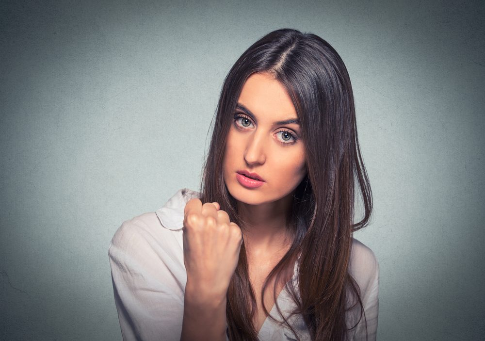 Young beautiful frustrated angry woman with fist up in air