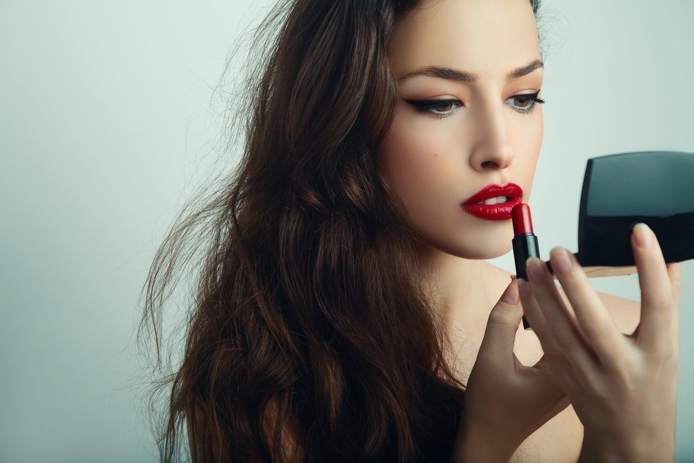 beautiful young woman apply red lipstick, studio shot