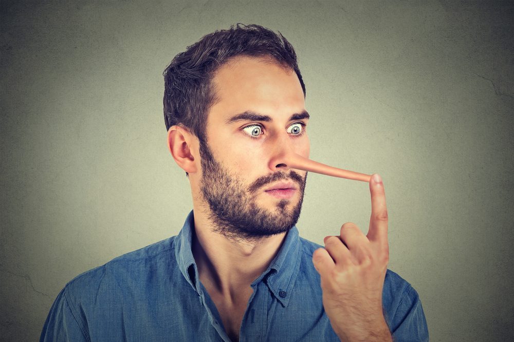 Man with long nose isolated on grey wall background. Liar concept. Human face expressions, emotions, feelings.