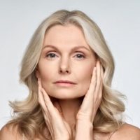 kobieta po pięćdziesiątce obejmująca twarz