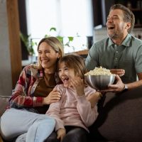 rodzinne oglądanie filmu w popcornem w domu