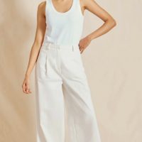 kobieta w białej bluzce i białych szerokich spodniach